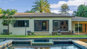 Una casa moderna con piscina, ventanas amplias y un césped bien cuidado.