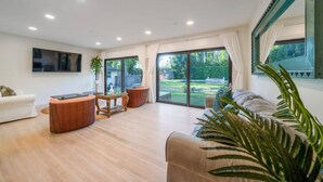 Un salón amplio con un sofá, una mesa de centro y un televisor montado en la pared.