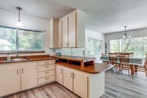 Une cuisine avec des meubles de rangement en bois, un plan de travail et un coin repas comprenant une table et des chaises.