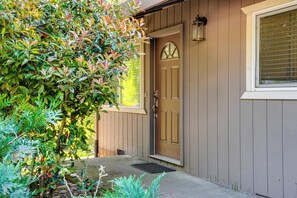 A wooden house with a brown door, a window with a grid pattern, and a small porch area. - Furnished Deck & Fire Pit: Sherwood Forest Cabin (Twain Harte)