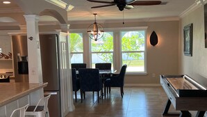 Une cuisine spacieuse avec un coin repas, une table de billard et un ventilateur de plafond.