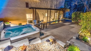 Ein Whirlpool, Sitzgelegenheiten im Freien und eine Terrasse mit Holzboden und Kies.