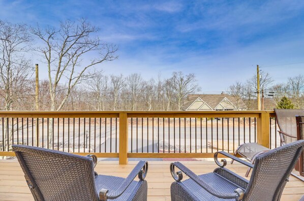 A deck with wicker chairs and a metal railing.