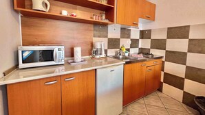 A compact kitchen with wooden cabinets, a microwave, a coffee maker, and a sink. - Holiday apartment with terrace, air conditioning and garden (Dramalj)