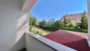 A balcony with a red roof, a view of a residential area, and a clear blue sky. - Holiday apartment with terrace, air conditioning and garden (Dramalj)
