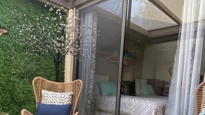Un espace extérieur aménagé, abrité et doté de mobilier en osier, ainsi que d’un mur végétal.