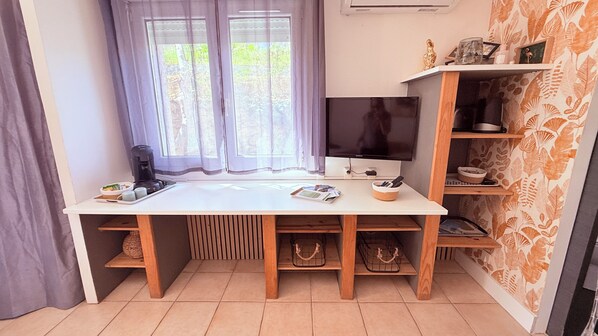 A room with a white desk, a computer, a coffee maker, and a shelf with decorative items. - Cité Paoline - Quiet Escape with Terrace Parking & Wi-Fi (Corte)