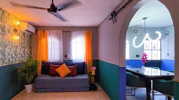 Une pièce comprenant un canapé, une table à manger et un ventilateur de plafond.