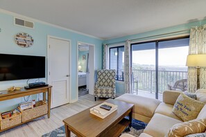Relax in this inviting living room with a sofa, armchair, and large window offering a view of the outdoors.