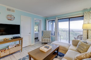 Relax in this inviting living room with a sofa, armchair, and large window offering a view of the outdoors.
