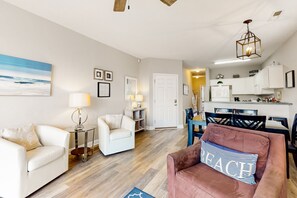 A modern living room with a dining area, a kitchen, and a hallway.
