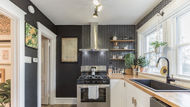Una cocina moderna con un salpicadero blanco y negro tipo espiga, electrodomésticos de acero inoxidable y una ventana con vistas.