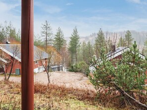 A rustic cabin with a dirt yard and a forested backdrop.