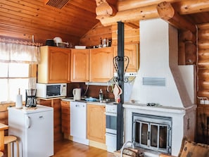 Une cuisine compacte avec des meubles de rangement en bois, un four à micro-ondes, une machine à café et une cuisinière.