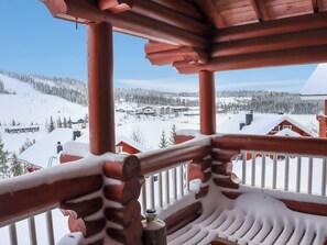 Un balcon en bois offrant une vue sur un paysage montagneux enneigé.