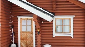 Eine Holzhütte mit einem verschneiten Veranda, einer Tür und einem Fenster.
