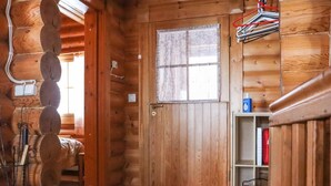 A wooden cabin interior with a door, a window with curtains, and a shelf with items. - Alppi 6b paritalo by Interhome (Hyrynsalmi)