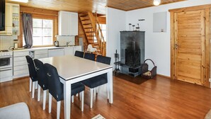 Een gezellig chaletinterieur met een eethoek, keuken en een open haard.