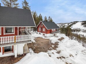 Un bâtiment à deux étages, à la façade rouge et doté d’un balcon, entouré d’un paysage enneigé et d’arbres.
