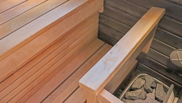 Een houten bank met een ingebouwde verwarming, een klein opbergvak en een vuurplaats van steen.