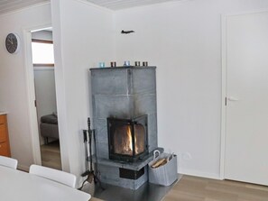 A room with a stone fireplace, a clock on the wall, and a door.