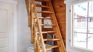 A wooden spiral staircase in a room with wooden walls and a window.