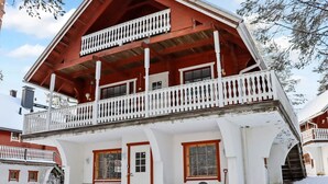 A two-story chalet with a balcony, wooden exterior, and snow-covered surroundings. - Alppikylä 8b by Interhome (Hyrynsalmi)