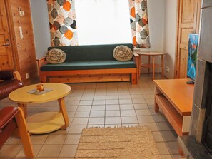 Een gezellige woonkamer met een houten bankje, een klein rond tafeltje en een open haard.