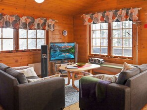 Un intérieur de chalet chaleureux avec une télévision, un canapé et une table.