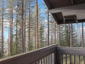 A wooden balcony with a view of tall pine trees. - Alppitalo mökki by Interhome (Hyrynsalmi)