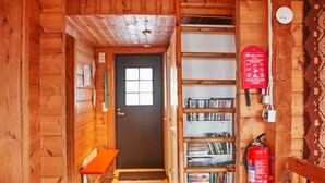 Un intérieur en bois avec une bibliothèque, un extincteur et une porte.