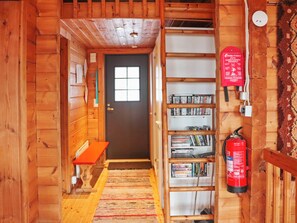 Un intérieur en bois avec une bibliothèque, un extincteur et un banc.