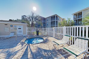 A pool area with lounge chairs, a hot tub, and a fenced deck.