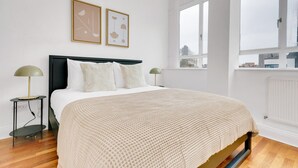 A bedroom with a bed, two bedside tables, a window, and two wall-mounted artworks. - Charming Old Street 1BR, 5 min walk to Old Street Tube, by Blueground (London)