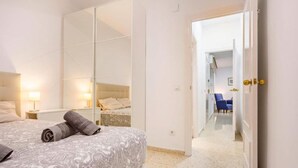 Ein Hotelzimmer mit Bett, großem Spiegel, Kleiderschrank und einer Tür zu einem Flur mit Sessel.