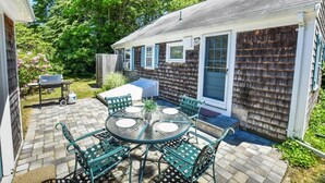 A patio with a round table and chairs, a grill, and a shed.