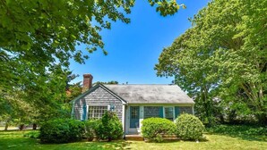 A small, single-story house with a sloped roof, a chimney, and a front porch.
