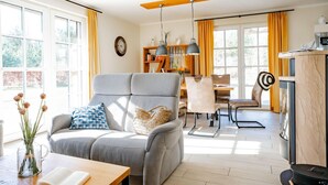 A modern living room with a grey sofa, a wooden coffee table, and a dining area with a table and chairs. - Vacation home Graukranich 41 - Holiday home Graukranich 41 - Close to nature (Fuhlendorf)