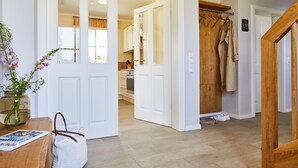 A hallway with a wooden door, a coat rack with clothes, and a wooden floor. - Vacation home Graukranich 41 - Holiday home Graukranich 41 - Close to nature (Fuhlendorf)