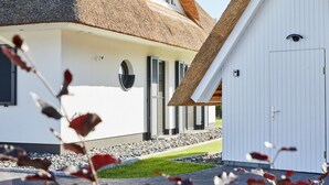 A modern building with a thatched roof, a white exterior, and a small attached shed. - Vacation home Graukranich 41 - Holiday home Graukranich 41 - Close to nature (Fuhlendorf)
