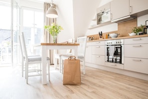 A modern kitchen with white cabinetry, a wooden countertop, and a large window.