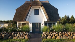 A house with a steeply pitched thatched roof, white exterior walls, and a central door. - Vacation home Seeschwalbe 44 - Holiday home Seeschwalbe 44 - Close to nature (Fuhlendorf)