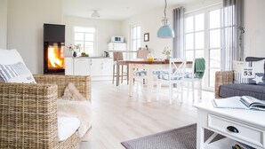 A cozy living room with a fireplace, a dining area, and a kitchen. - Vacation home Seeschwalbe 44 - Holiday home Seeschwalbe 44 - Close to nature (Fuhlendorf)