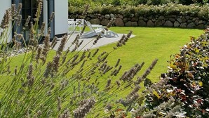 A white house with black shutters, a stone wall, and a well-maintained lawn. - Vacation home Seeschwalbe 44 - Holiday home Seeschwalbe 44 - Close to nature (Fuhlendorf)