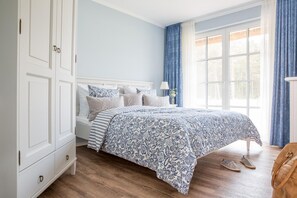 Une chambre à coucher avec un lit, une table de chevet, une lampe et une fenêtre avec des rideaux.