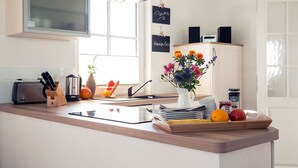 Eine moderne Küche mit Holzarbeitsplatte, einem Toaster, einem Wasserkocher und einer Vase mit Blumen. An der Wand befinden sich Schilder und über der Spüle ein Fenster.