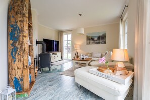 A living room with a sofa, a TV, a wooden bookshelf, and a lamp.