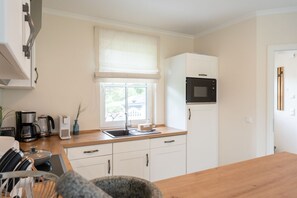 Una cocina con un lavamanos, microondas, armarios y una ventana con vistas al exterior.