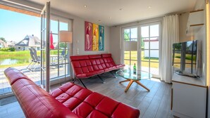 Amplia sala de estar con un sofá rojo, una mesa de centro de vidrio y un televisor sobre un mueble.