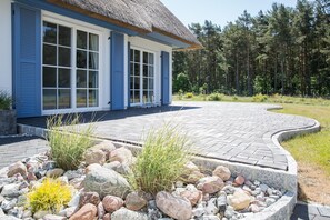 Et moderne hus med stråtækt tag, store vinduer og en belagt indkørsel, der fører til en stensti.